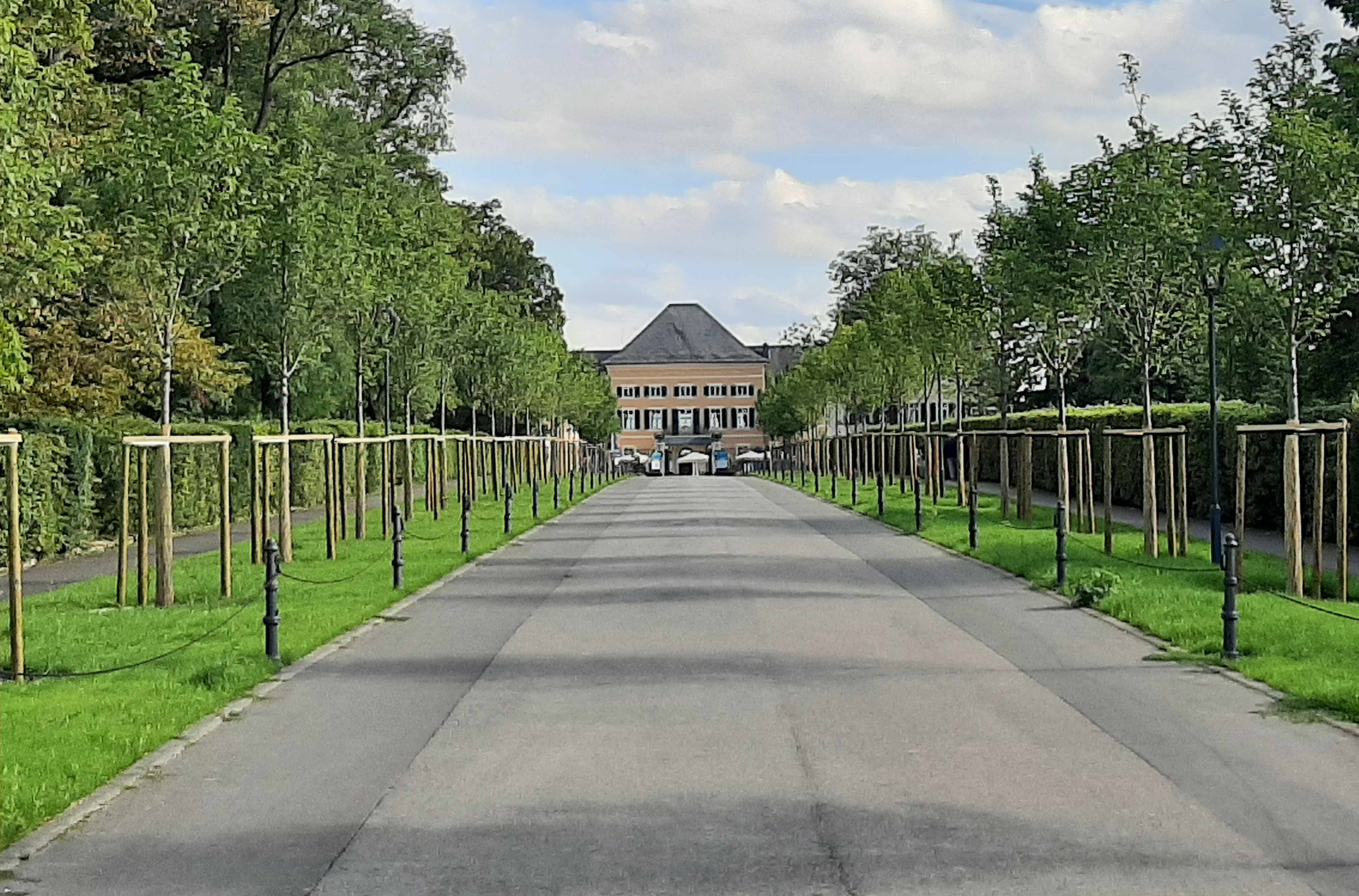 Eine breite Straße führt auf das Schloss im Bildhintergrund zu.