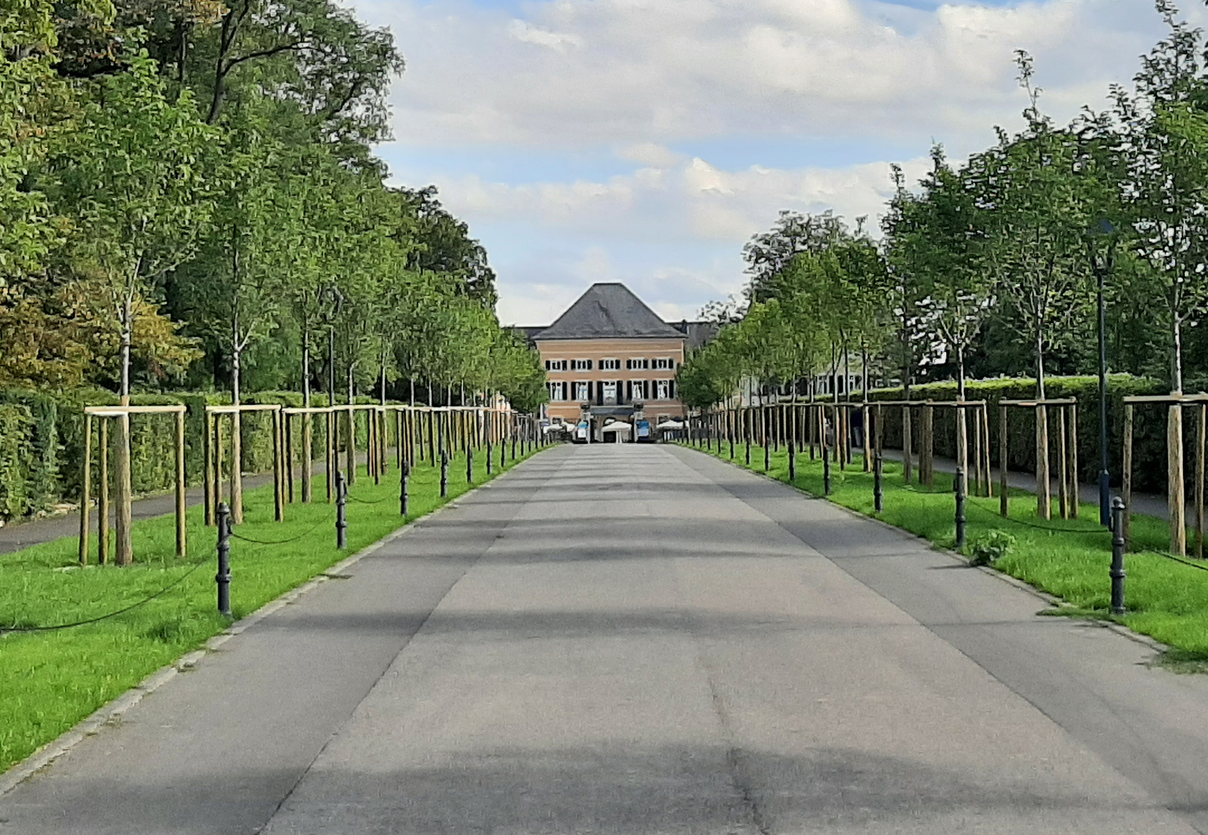 Eine breite Straße führt auf das Schloss im Bildhintergrund zu.