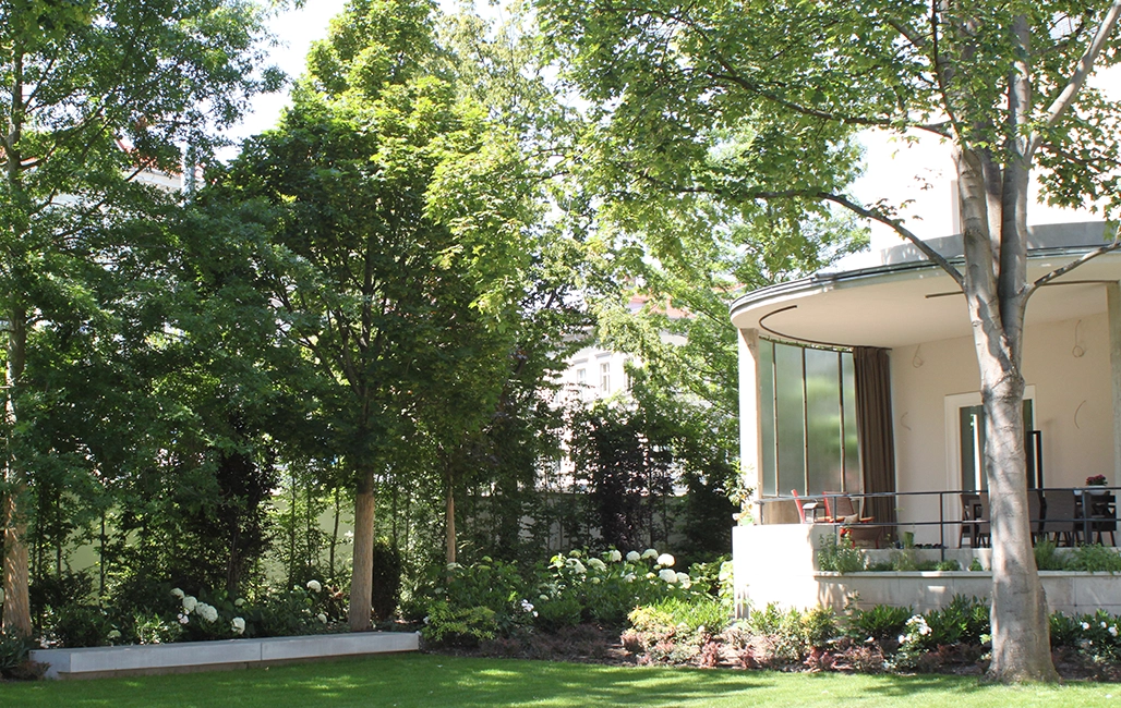 Ein Privatgarten mit großen Bäumen die Schatten spenden